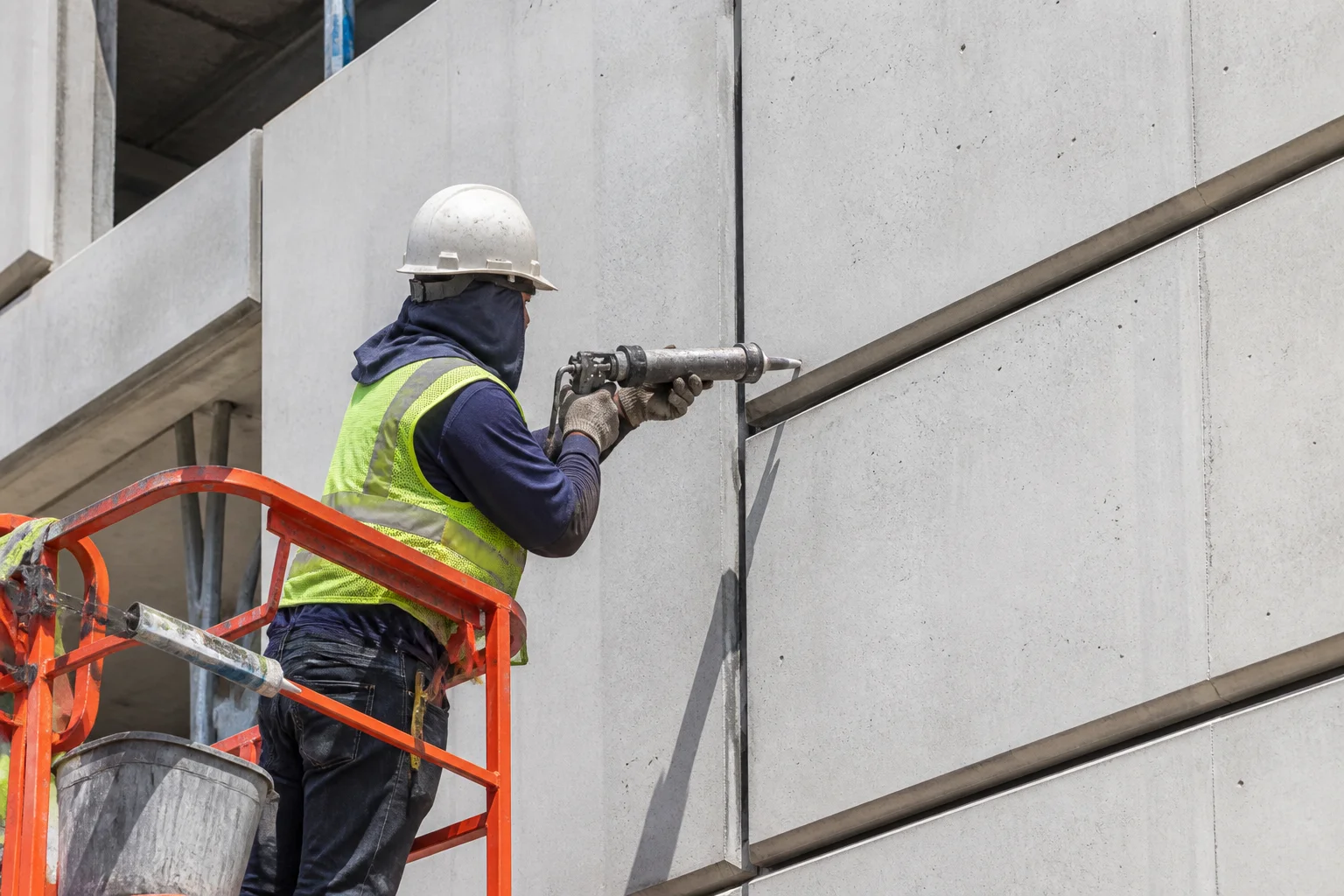 Pekerja konstruksi mengaplikasikan sealant pada sambungan vertikal antara panel beton pracetak pada fasad bangunan